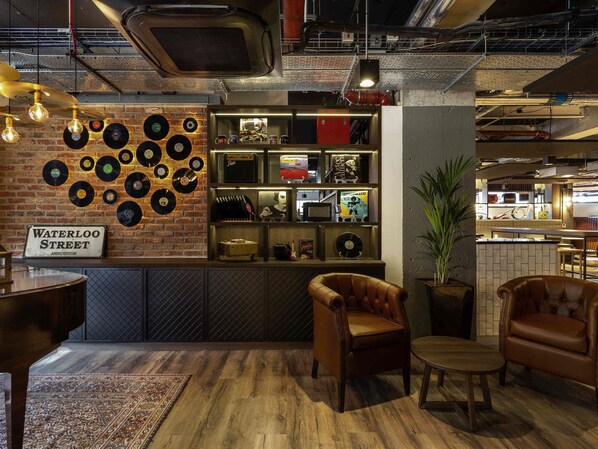 A cozy lounge area with a brick wall, vinyl records, and leather furniture. - Ibis Styles Glasgow Central (Glasgow)