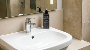 Un baño con un lavamanos blanco, un espejo y una botella de producto capilar.