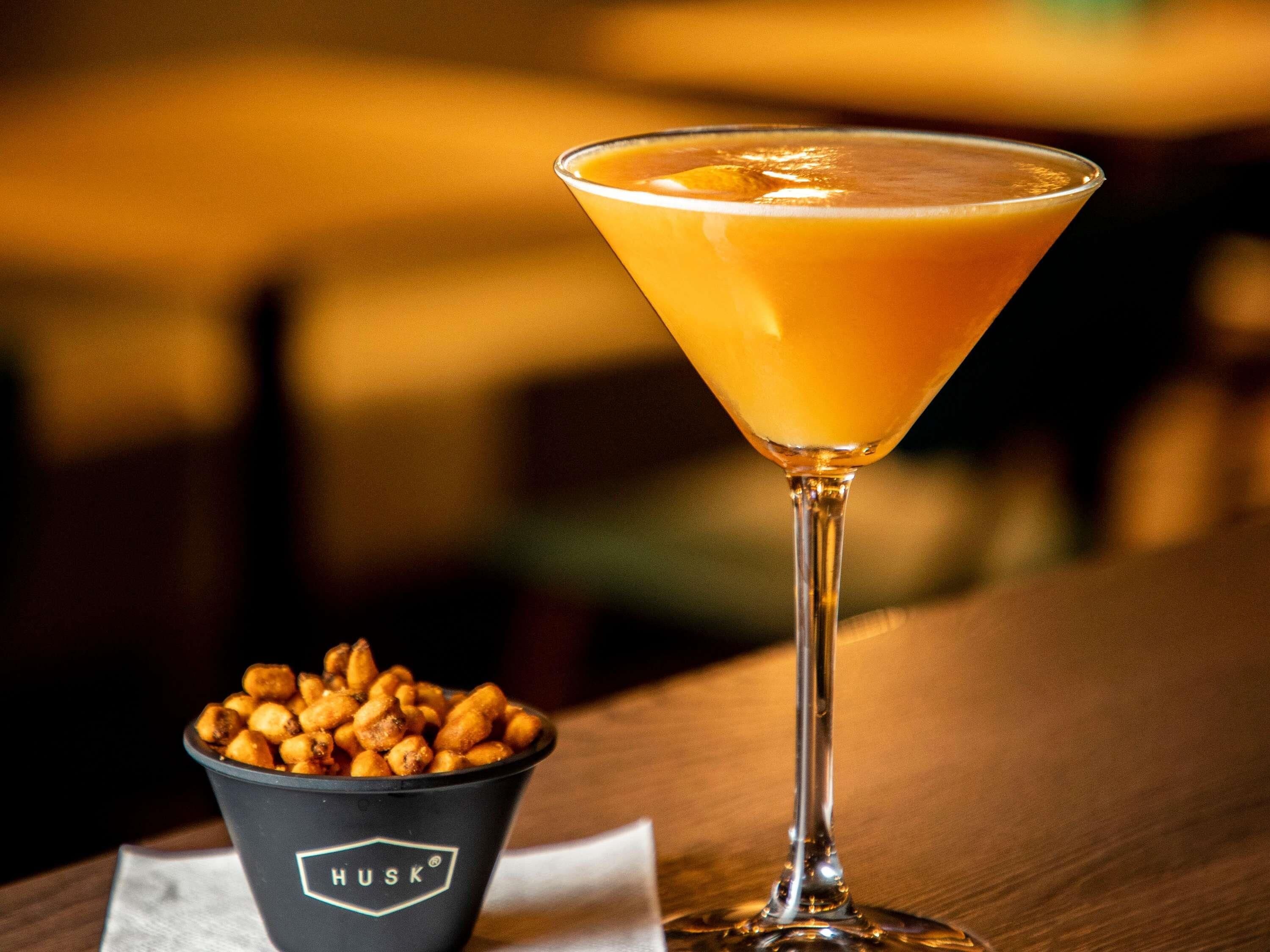 A martini glass with a clear liquid on a wooden table.