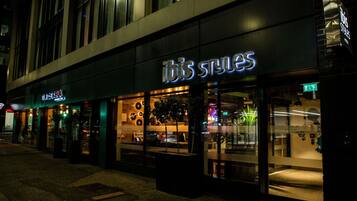 Un edificio con escaparate que muestra la leyenda 'ibis styles' de noche.