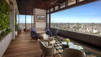 A modern lounge with a city view, wooden flooring, and contemporary furniture.