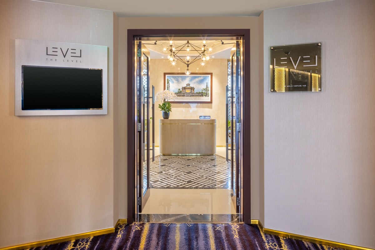 A hotel entrance with a reception desk, a chandelier, and two signs with 'LEVEL' branding.