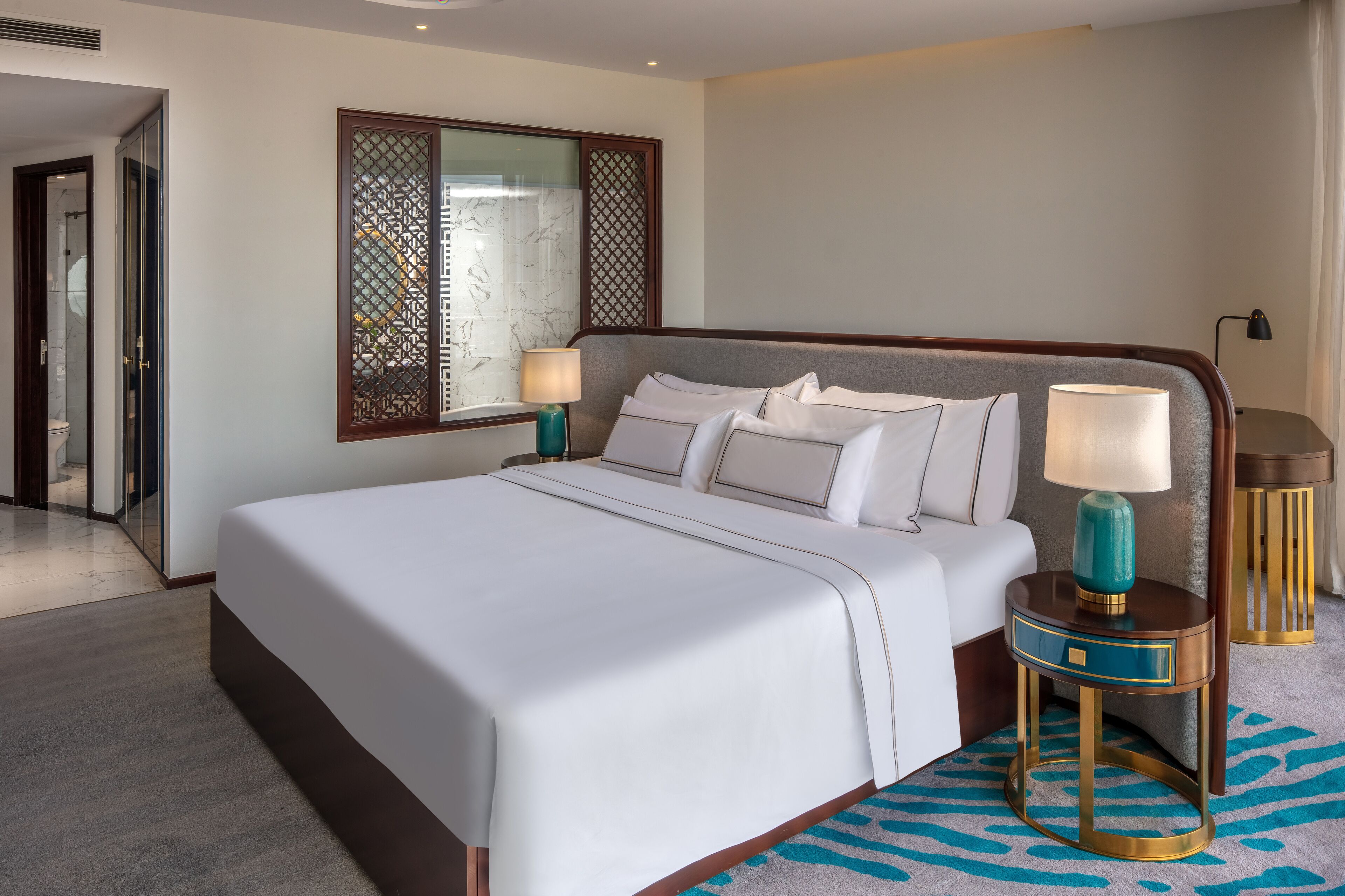 A neatly made bed with white linens, a wooden headboard, and two bedside tables with lamps.