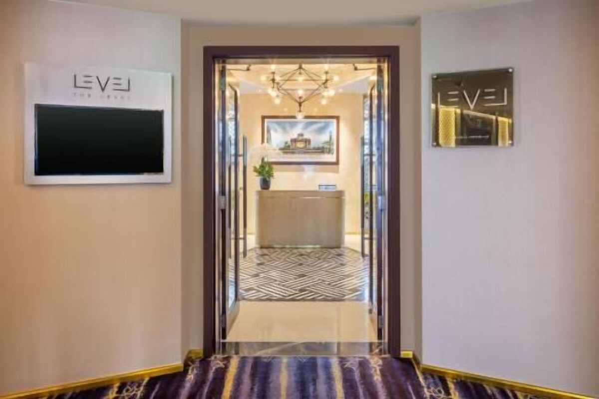 A hotel entrance with a reception desk, a chandelier, and a patterned carpet.