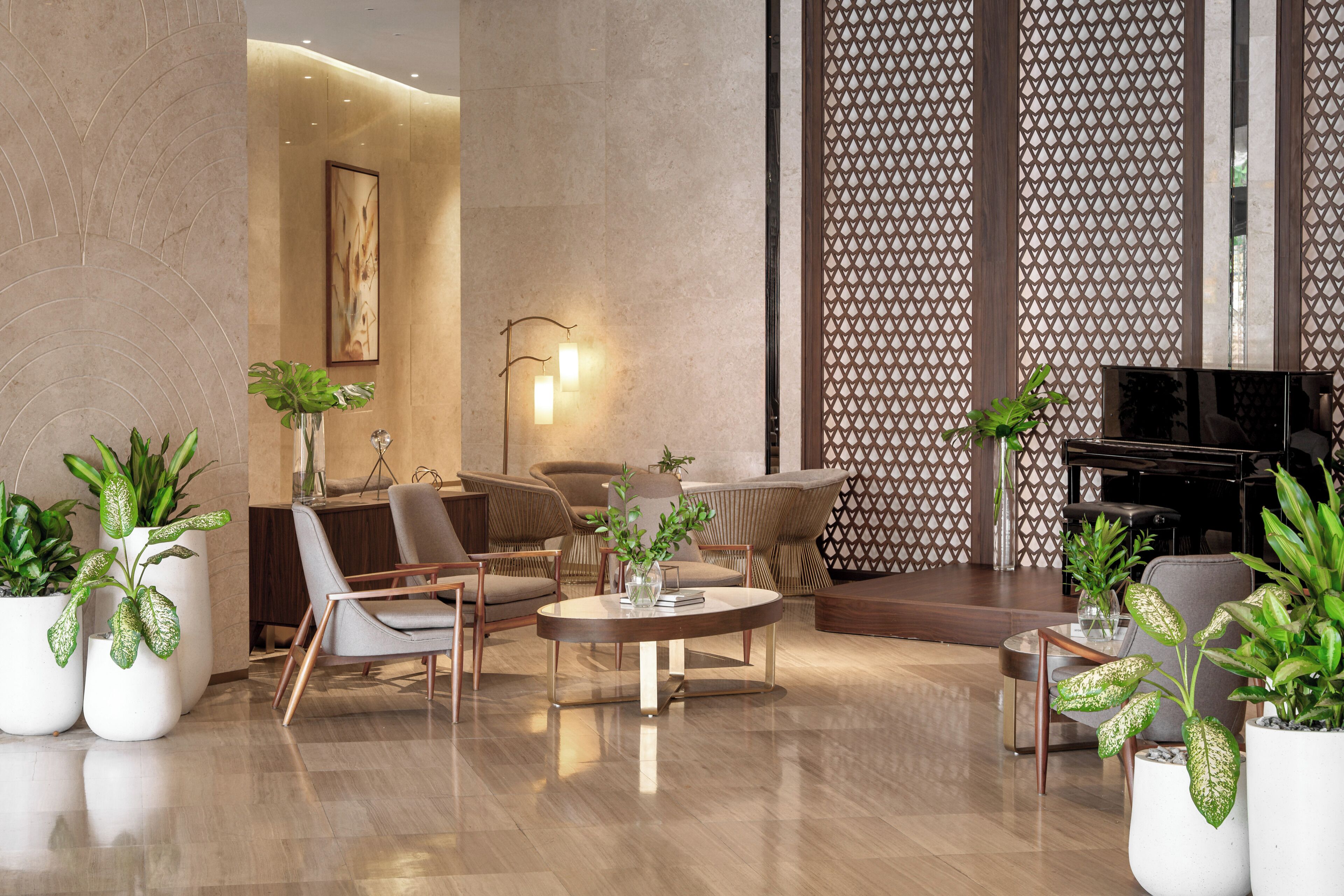 A modern lobby with a round coffee table, comfortable seating, and potted plants.