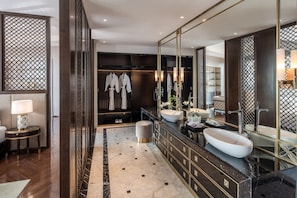 A modern bathroom with a large mirror, two sinks, and a walk-in closet with robes.