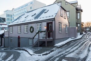 Un edificio de dos pisos con techo nevado y un porche delantero.