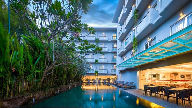 A hotel with a swimming pool, outdoor seating, and a modern building facade. - Kuta Galleria Hotel (Kuta)