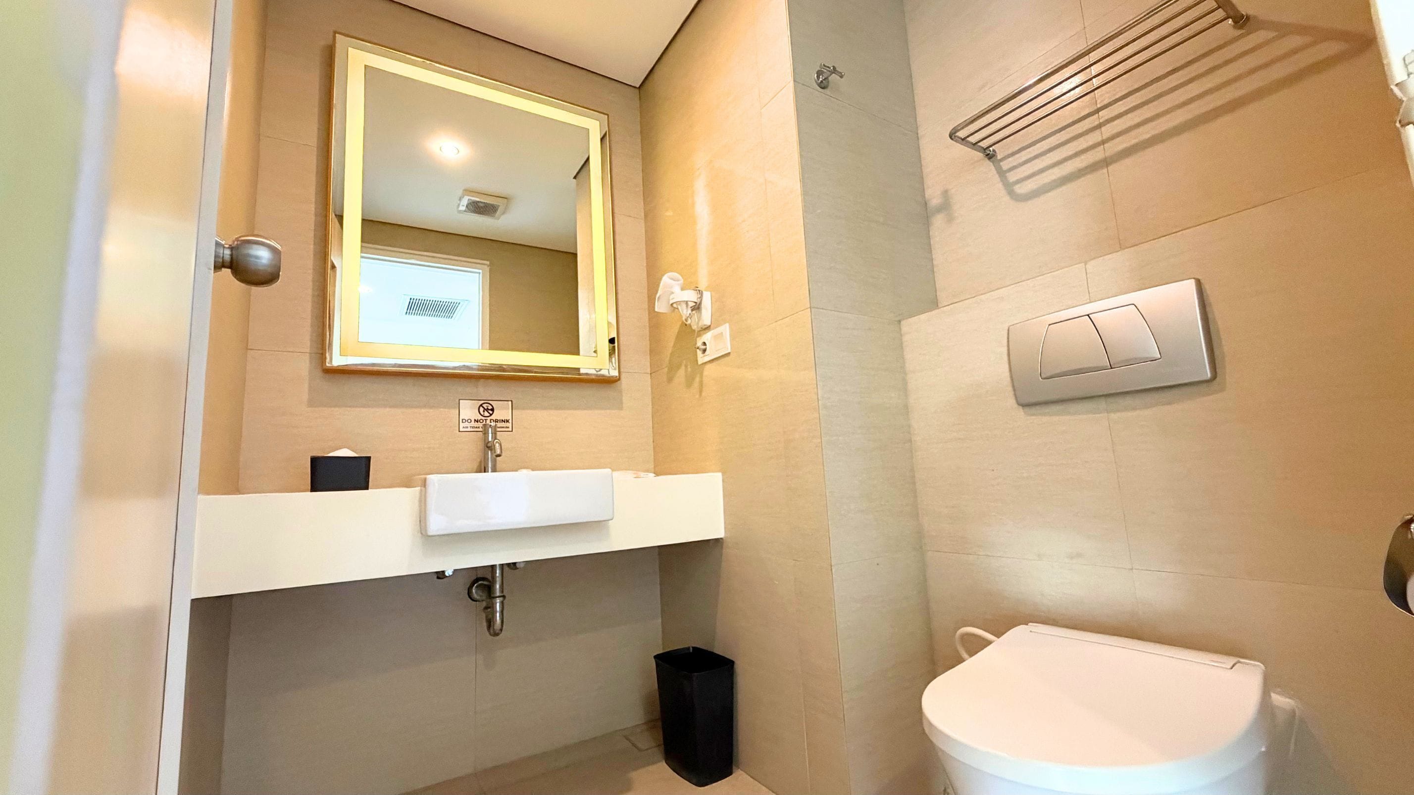 A bathroom with a white sink, a mirror, a toilet, and a towel rack.