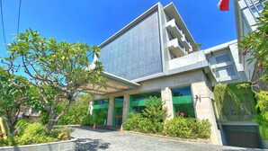 A modern building with a large glass facade, green-tinted windows, and a covered entrance area. - Kuta Galleria Hotel (Kuta)