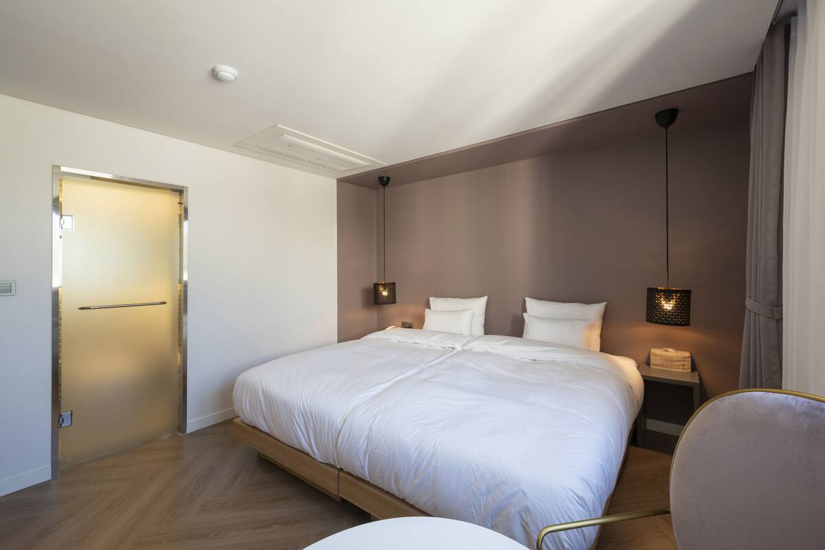 Et moderne hotelværelse med en stor seng, sengeborde og en lampe i loftet.