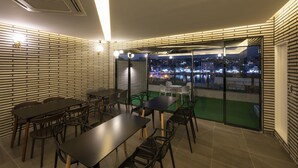 Un comedor moderno con mesas y sillas, vistas a la ciudad a través de amplios ventanales y un diseño de pared de ladrillo.