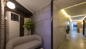 Un pasillo moderno con sofá, planta en maceta y aire acondicionado de pared.
