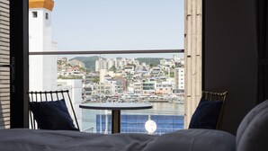Habitación de hotel con balcón con vistas a un puerto deportivo y al paisaje urbano.