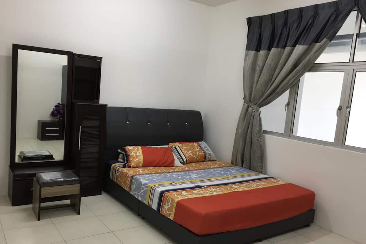 A bedroom with a bed, a dresser, a mirror, and a window with curtains.