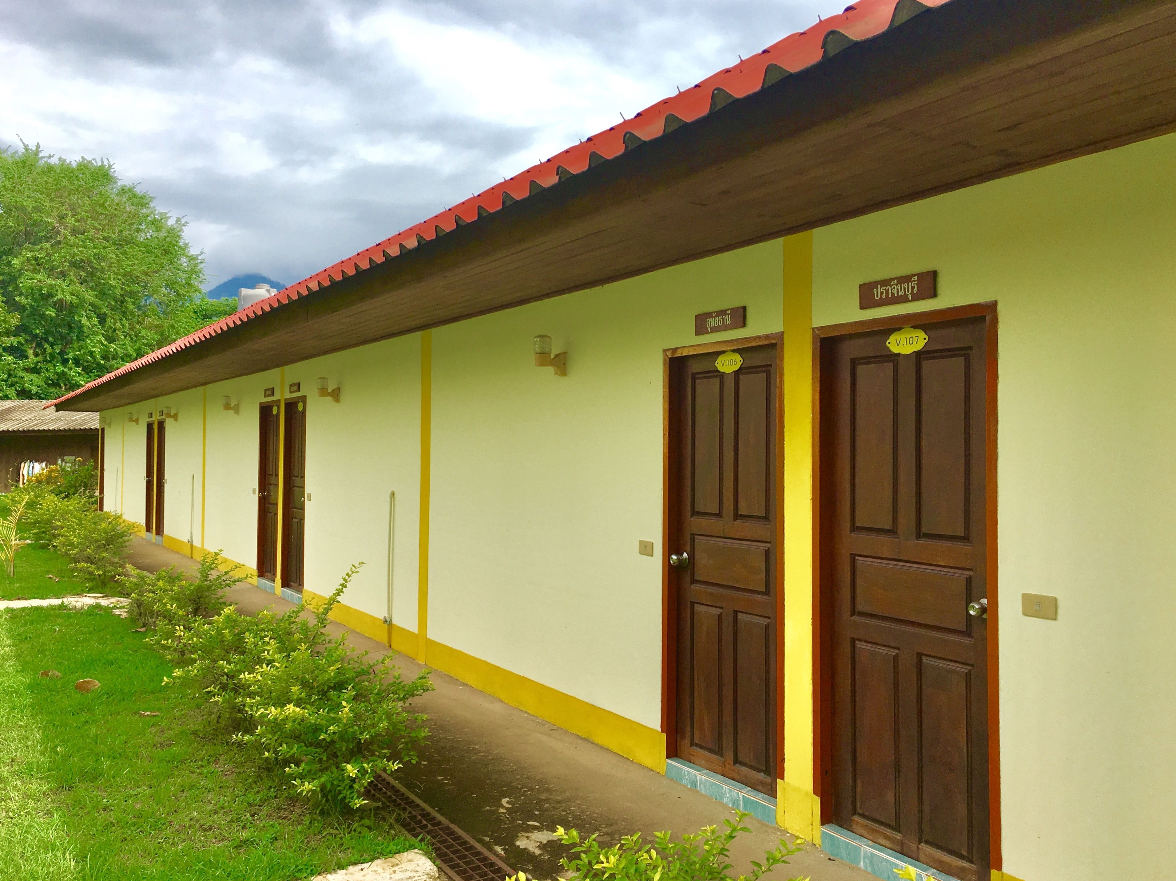 A row of wooden doors with yellow trim and a green wall, each marked with a number.