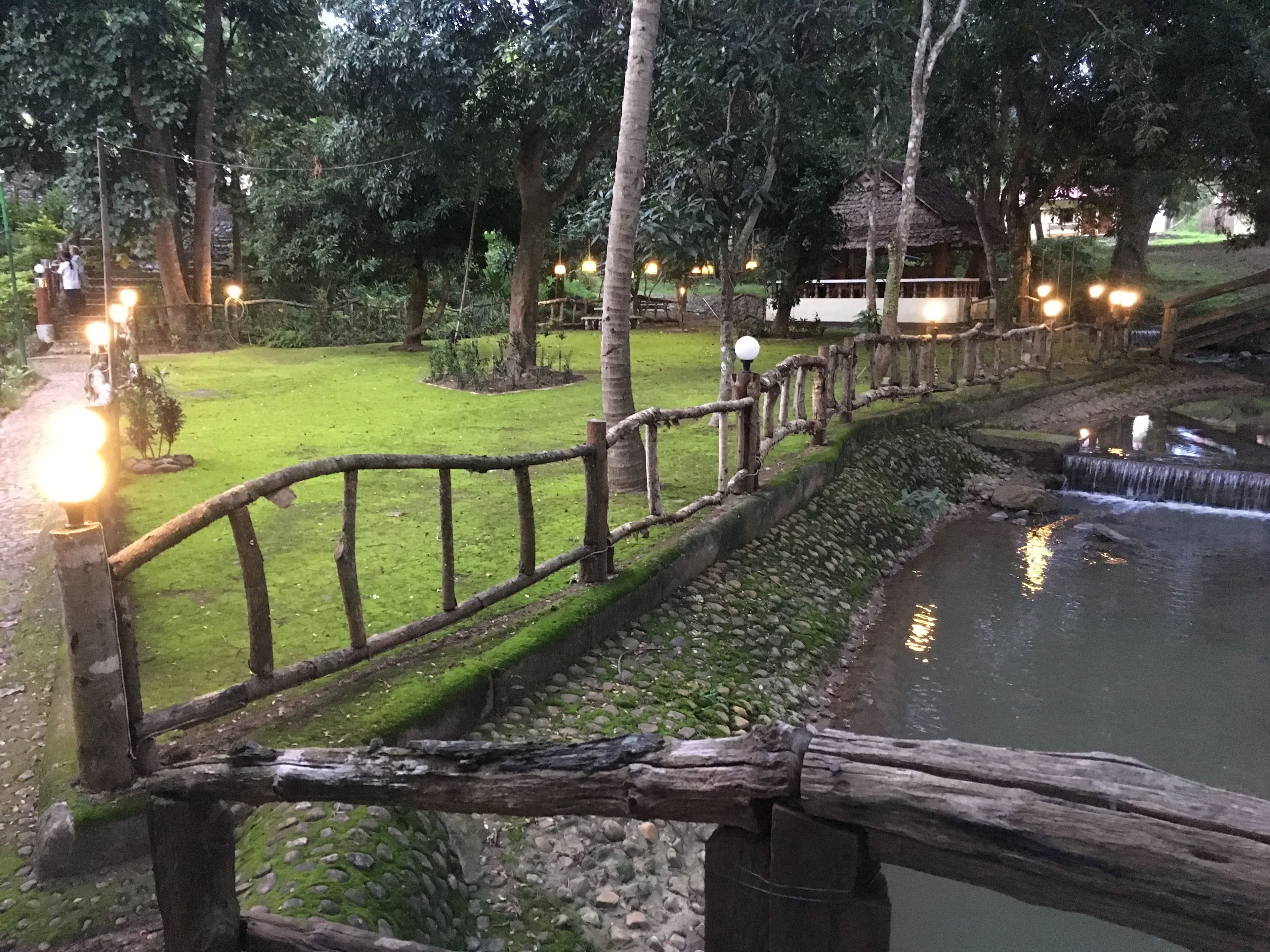 A wooden fence along a water feature in a park setting.