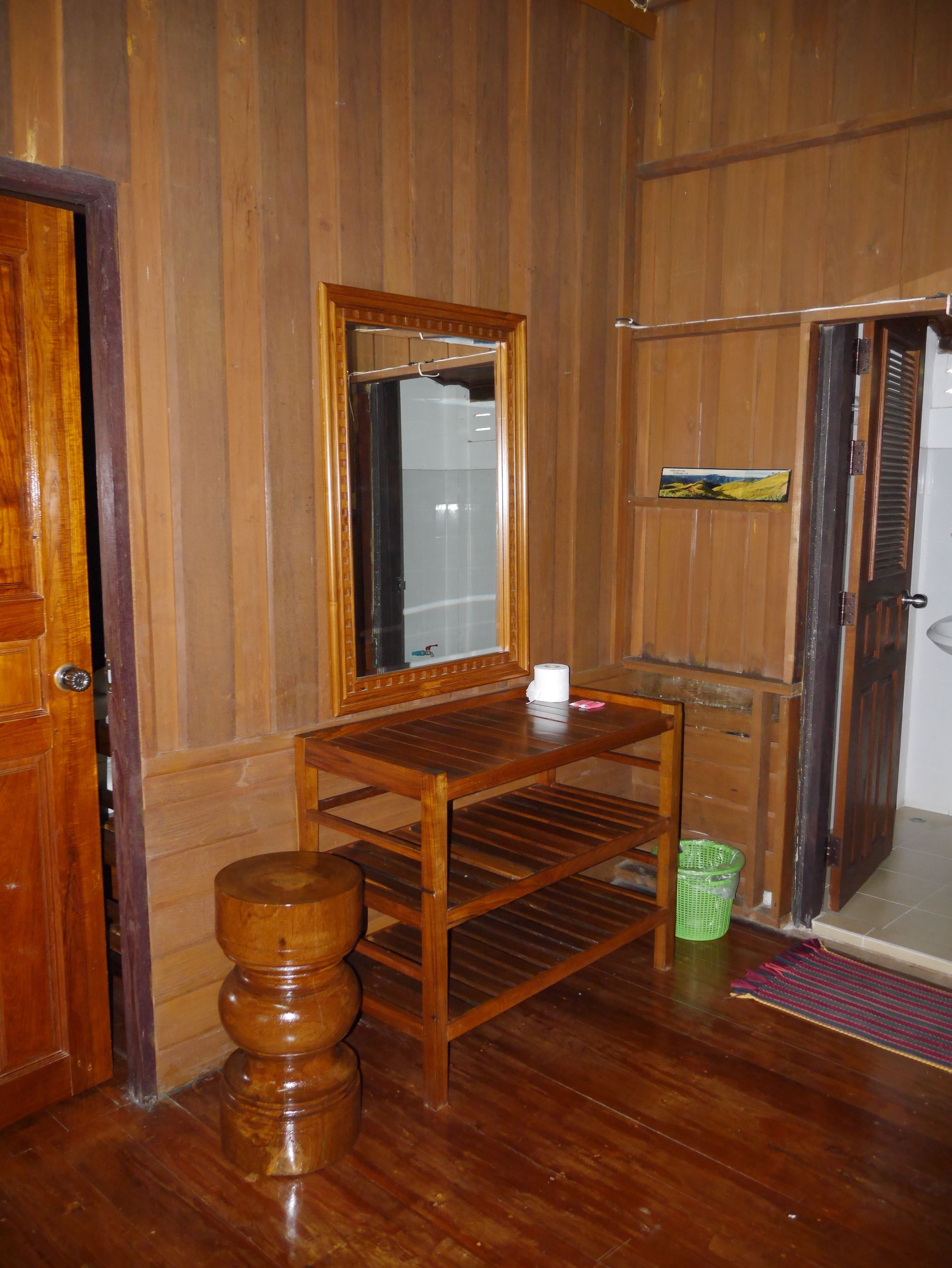 A wooden room with a wooden table, a mirror, a green basket, and a door.
