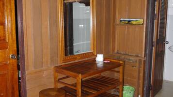 A wooden room with a wooden table, a mirror, a green basket, and a door.