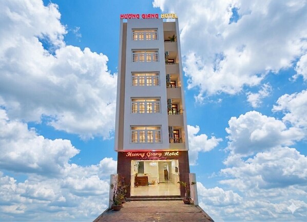 Un hôtel à plusieurs étages, avec un ciel dégagé et des nuages en arrière-plan.