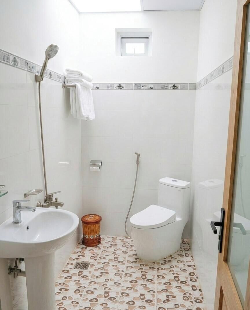 A bathroom with a sink, toilet, shower, and a small window.