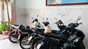 Twee motorfietsen staan binnen, een lijst met een schilderij aan de muur en een potplant.