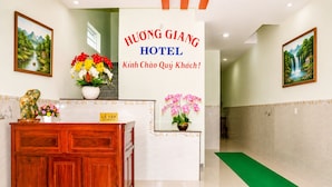 Een hotel receptie met een bord waarop 'HUONG GIANG HOTEL' en 'Welkom gewaardeerde gasten!' staat.