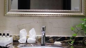 A bathroom with a marble sink, a large mirror, and toiletries on the counter. - Bojue Hotel (Jiaxing)