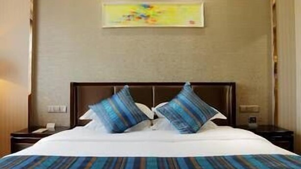 A hotel room with a large bed, two nightstands, a wall-mounted painting, and a ceiling light. - Bojue Hotel (Jiaxing)