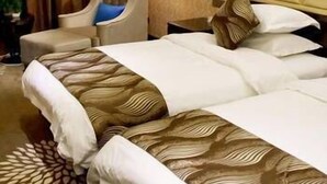 A hotel room with a large bed, a chair, a lamp, and a patterned carpet. - Bojue Hotel (Jiaxing)