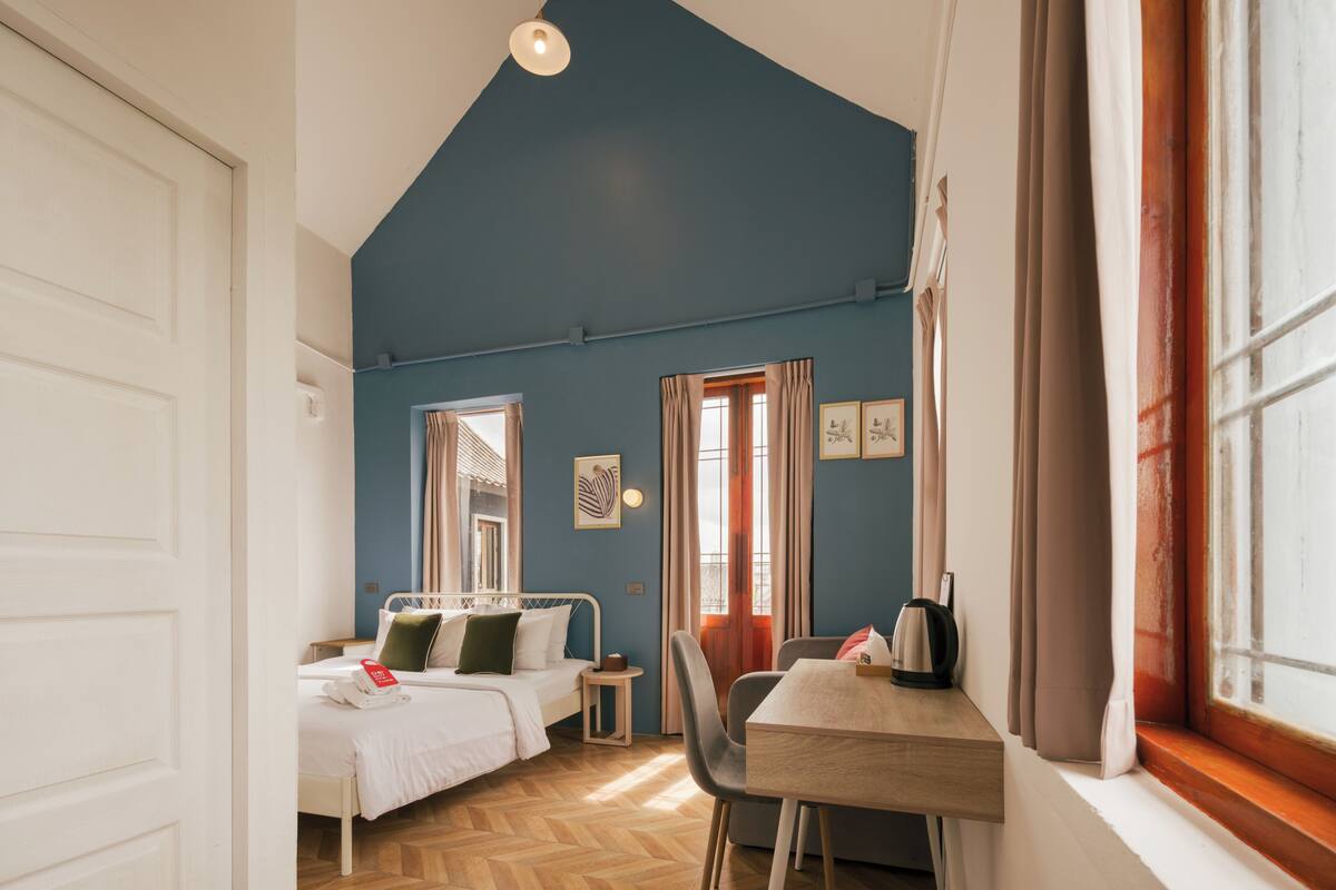Een slaapkamer met een bed, nachtkastje en een raam met gordijnen.