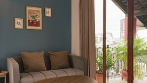 Ein modernes Wohnzimmer mit einer Couch, einem Holztisch und Blick auf die Stadt durch große Fenster.