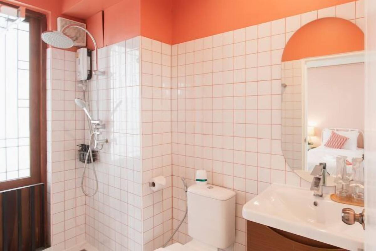 Een badkamer met douche, toilet, wastafel en spiegel.