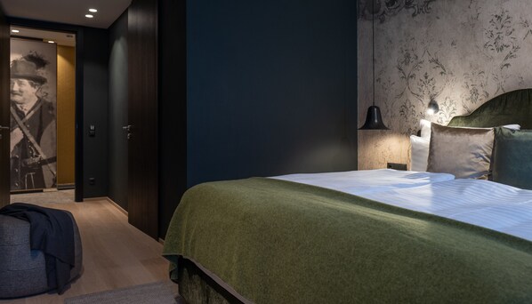 A modern bedroom with a large bed, a nightstand, a lamp, and a wall-mounted headboard. - SISSI SUITES luxury apartments (Mayrhofen)