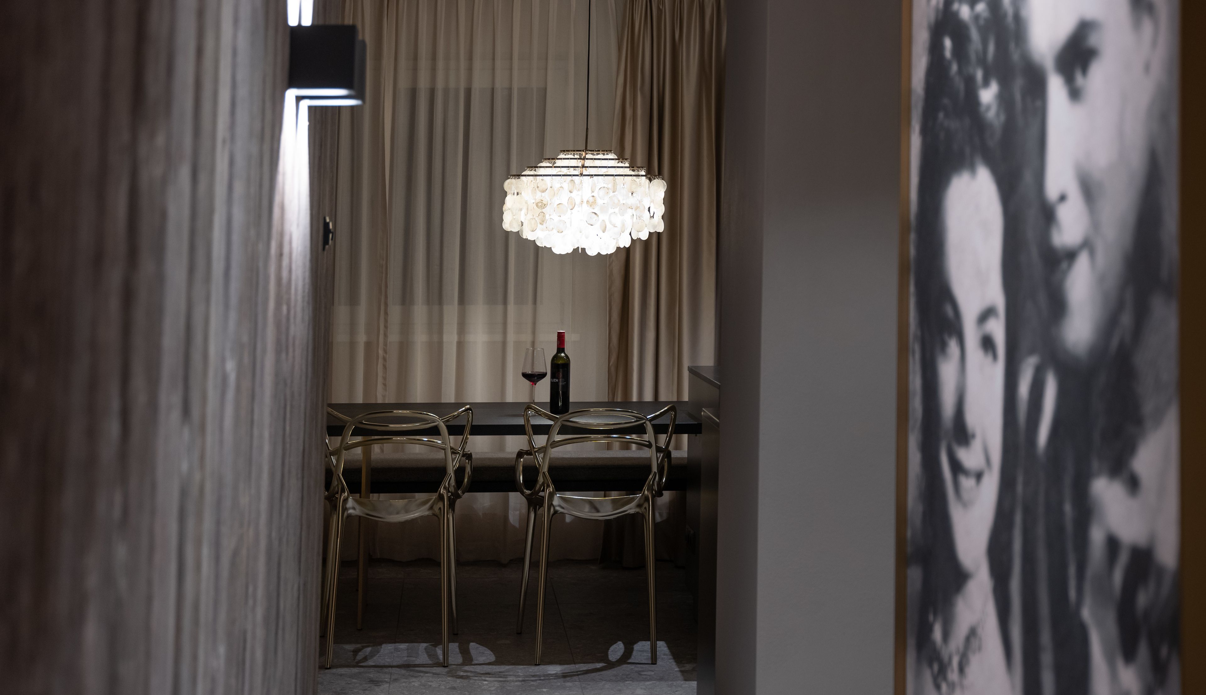 Un coin repas agrémenté d’un lustre, d’une table et de deux chaises.
