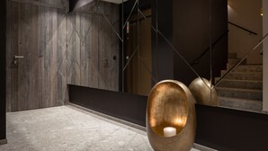 Um interior moderno com parede de madeira, elevador de vidro e escada.
