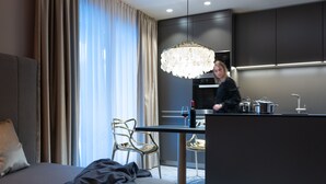 Quarto de hotel moderno com cama, área de refeições e cozinha compacta.