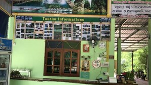 Un point d’information touristique à la façade verte, doté d’une grande fenêtre et d’une enseigne.
