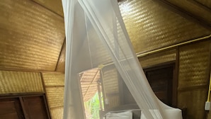 Un lit à baldaquin, avec une tête de lit en bois et un matelas recouvert de draps blancs.