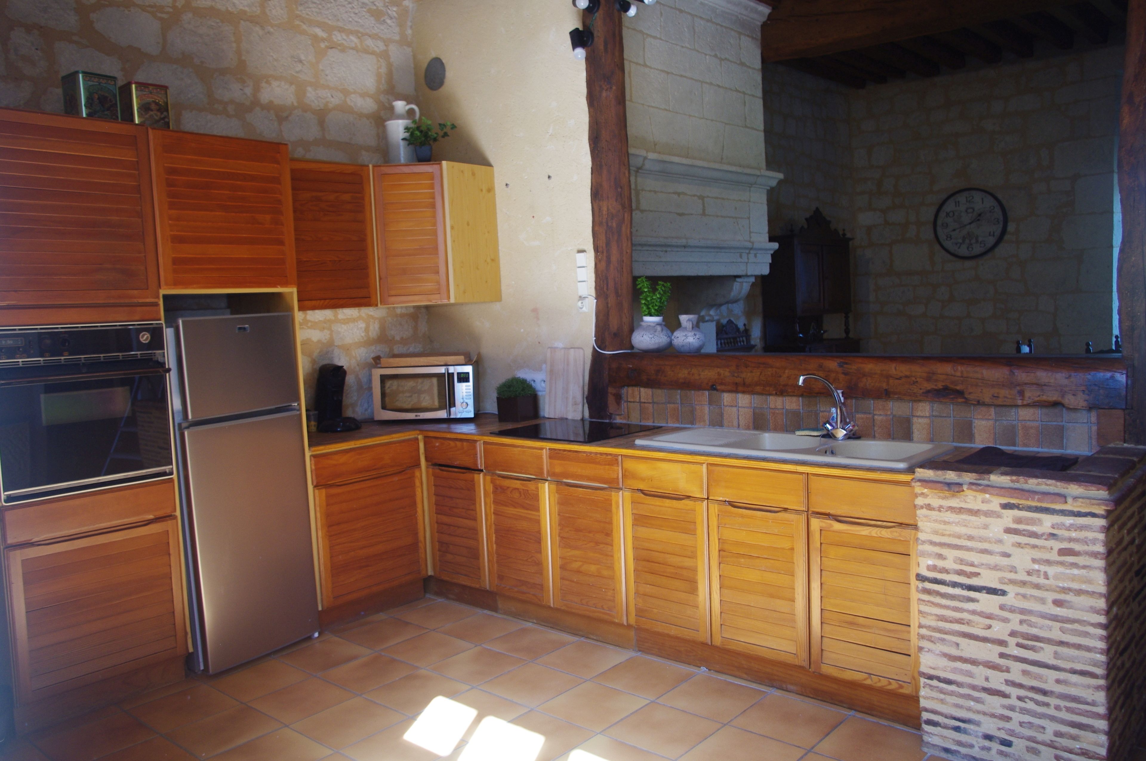 A kitchen with wooden cabinets, a stainless steel refrigerator, a microwave, and a sink.
