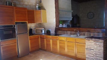 A kitchen with wooden cabinets, a stainless steel refrigerator, a microwave, and a sink.
