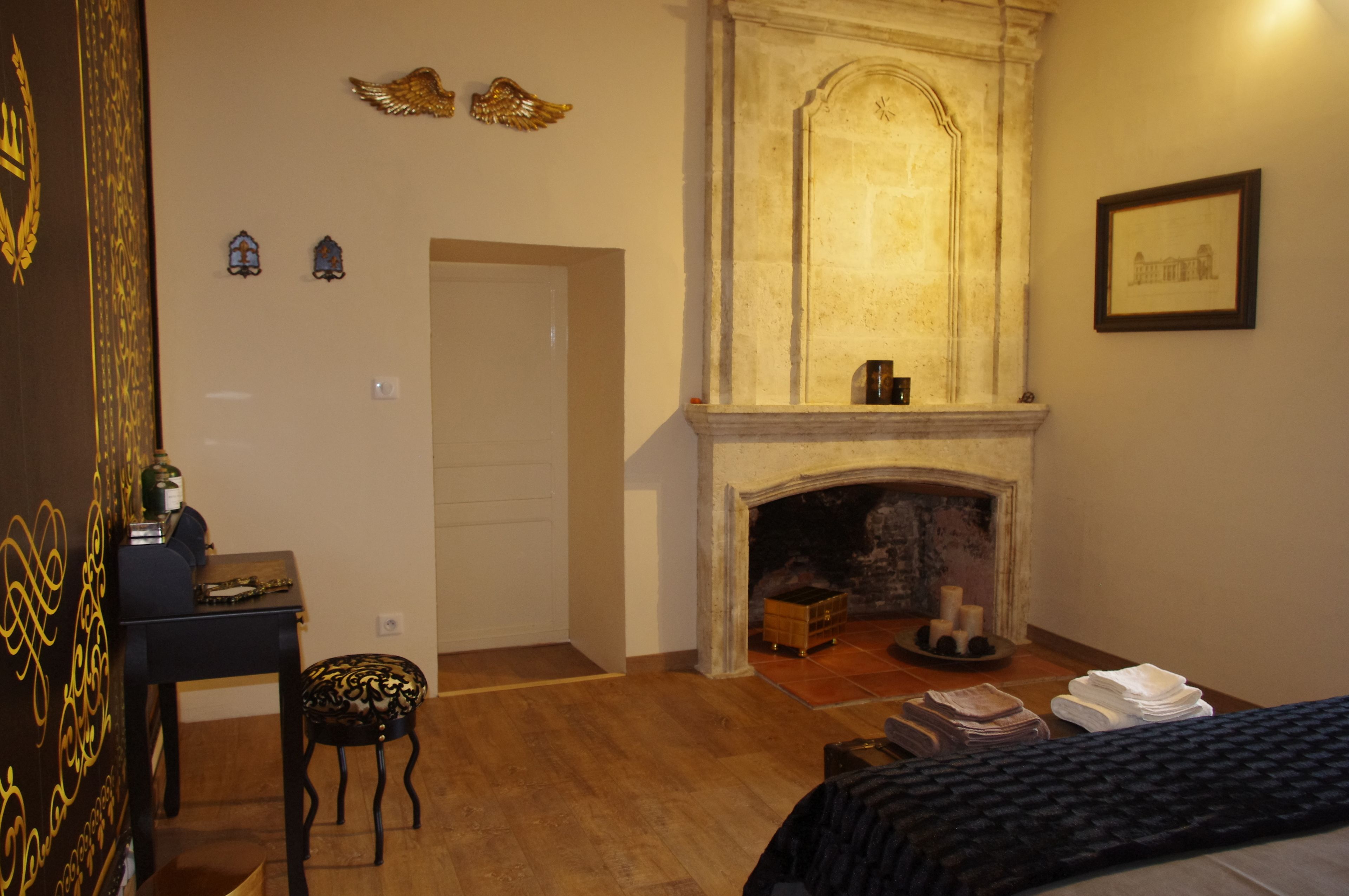 Una habitación con chimenea, cama, escritorio y silla.