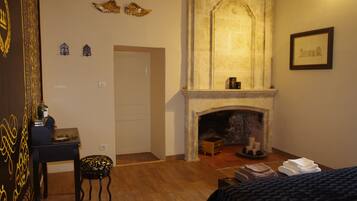 Una habitación con chimenea, cama, escritorio y silla.