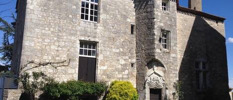 A stone building with a central entrance, large windows, and a small tower.