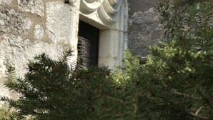 A stone building with a carved doorway and a metal gate.