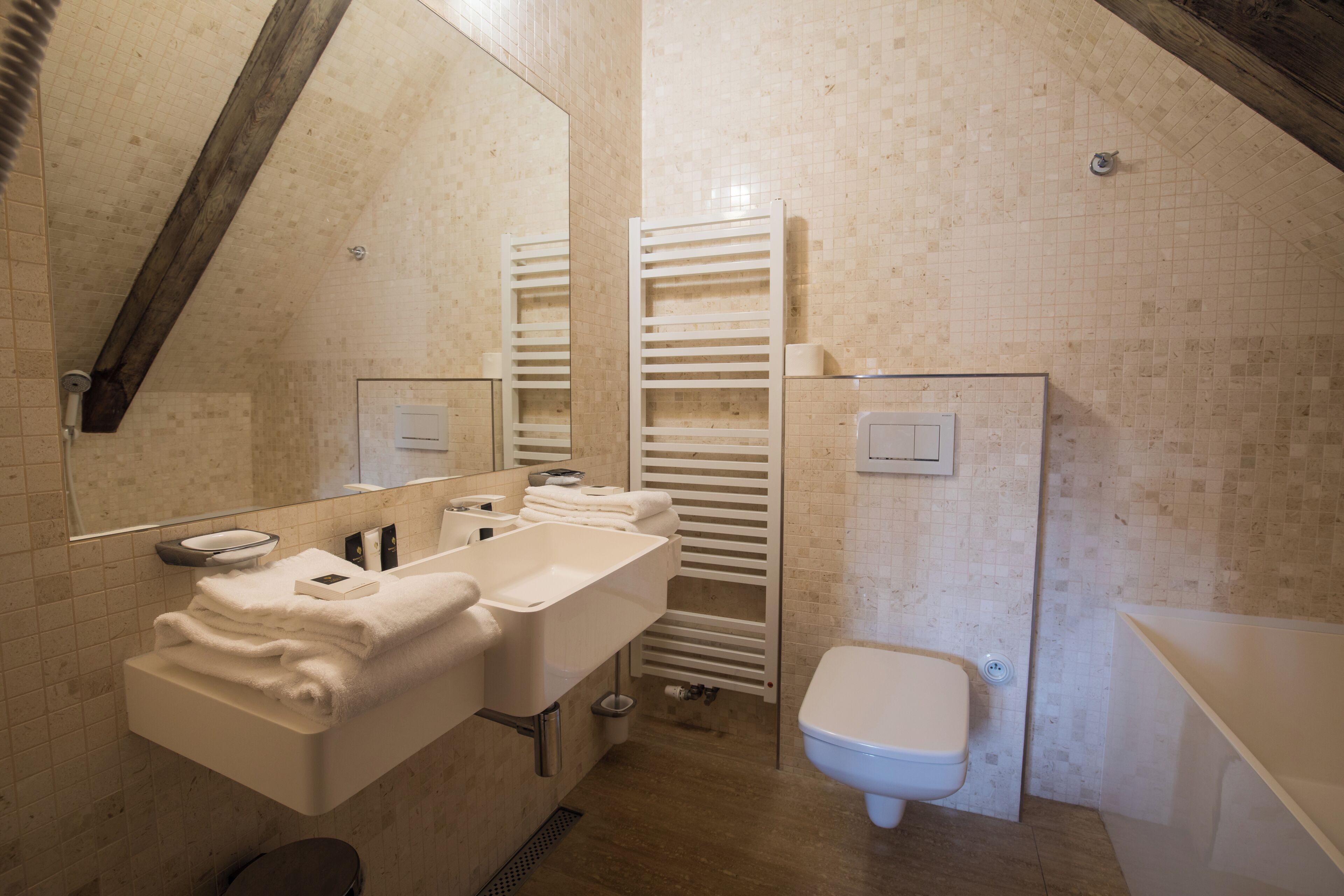 Un baño con lavamanos, espejo, toallero, inodoro y zona de ducha.