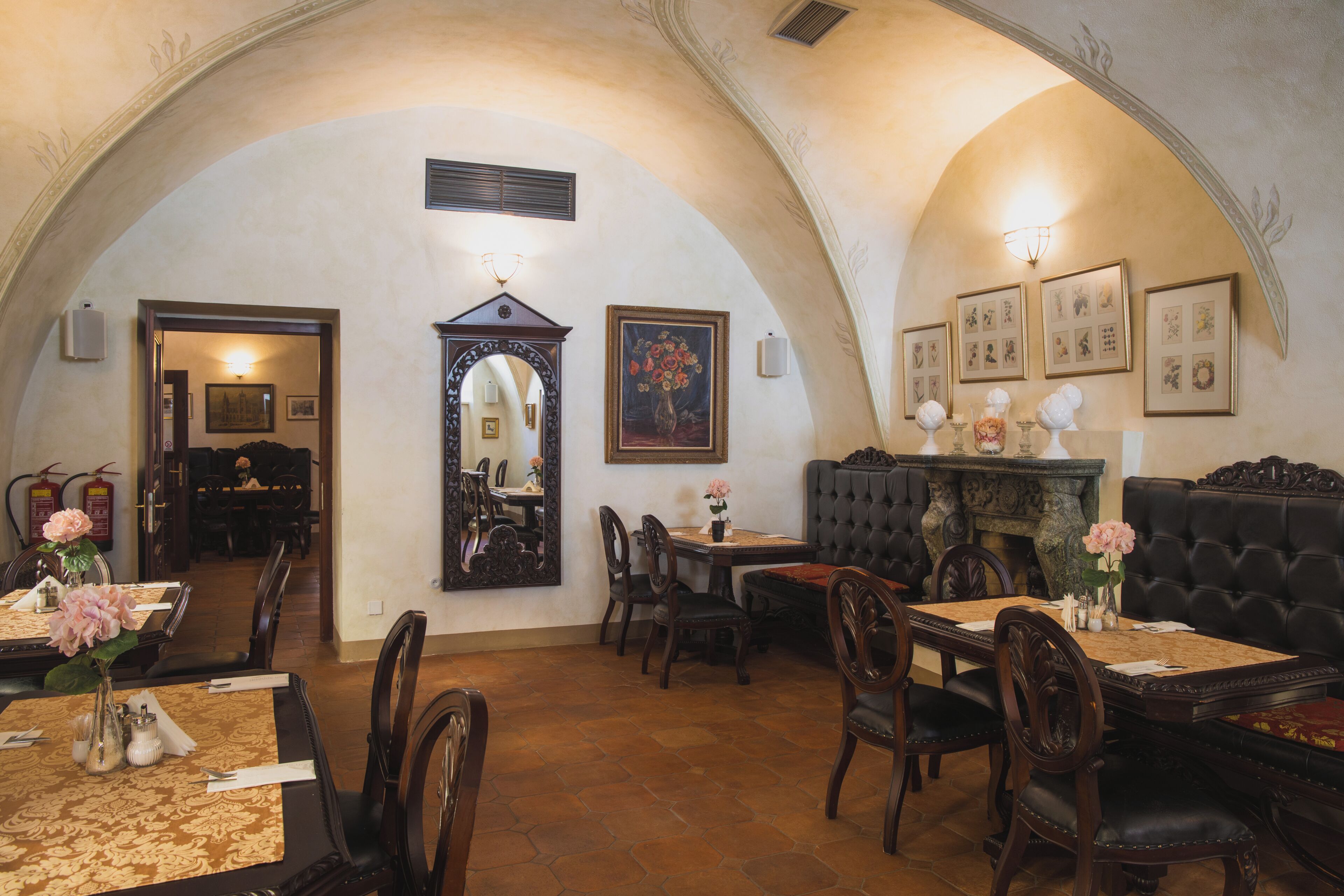 Un comedor con mesas, sillas, chimenea y obras de arte enmarcadas en las paredes.