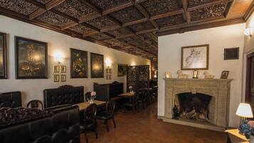 A dining area with wooden furniture, a fireplace, and framed artwork on the walls.