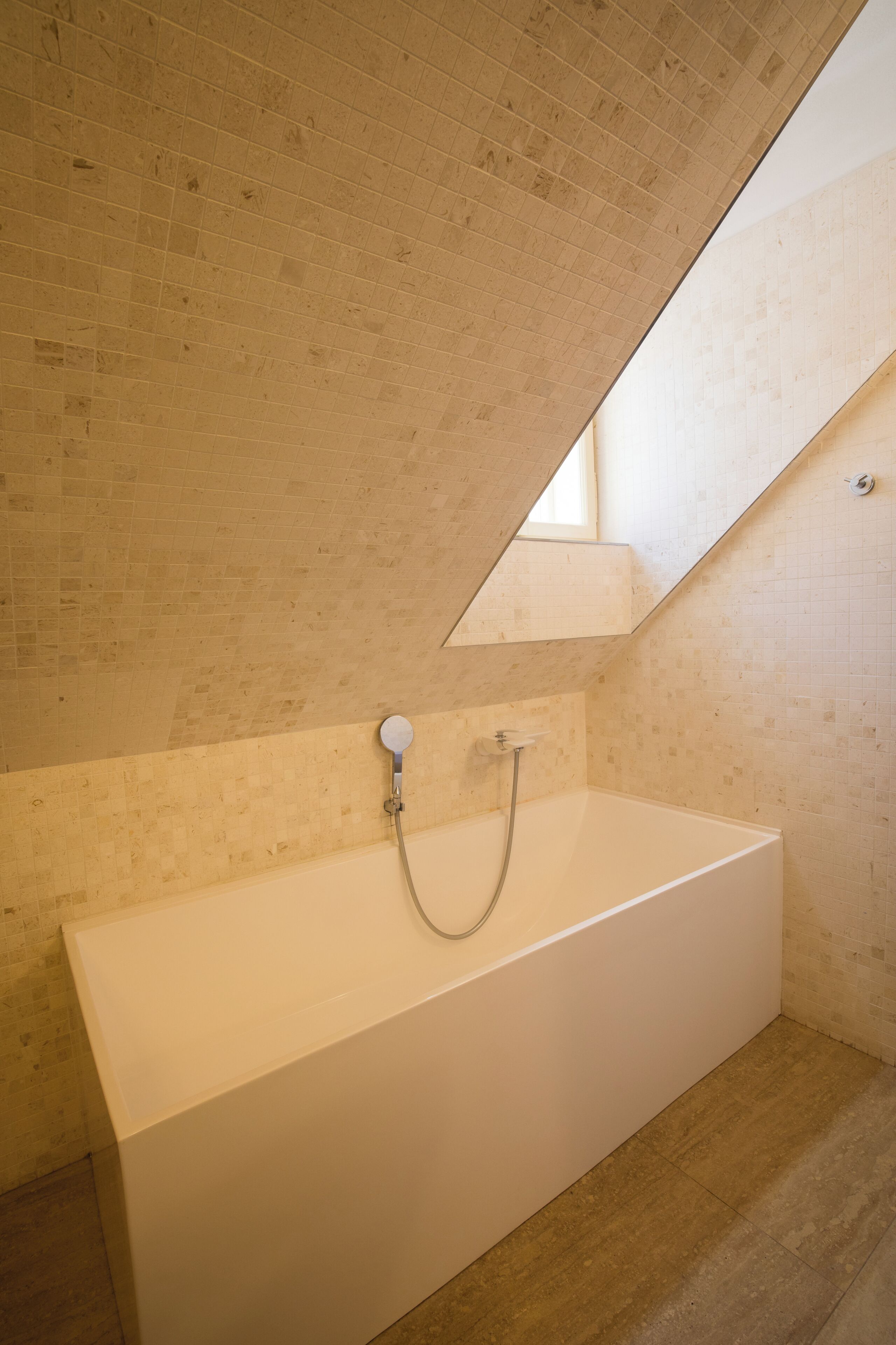 A modern bathroom with a bathtub, a shower, and a sloped ceiling.
