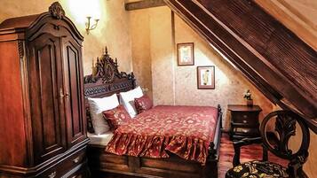 A bedroom with a wooden bed, a chest of drawers, a small table, and a decorative chair.